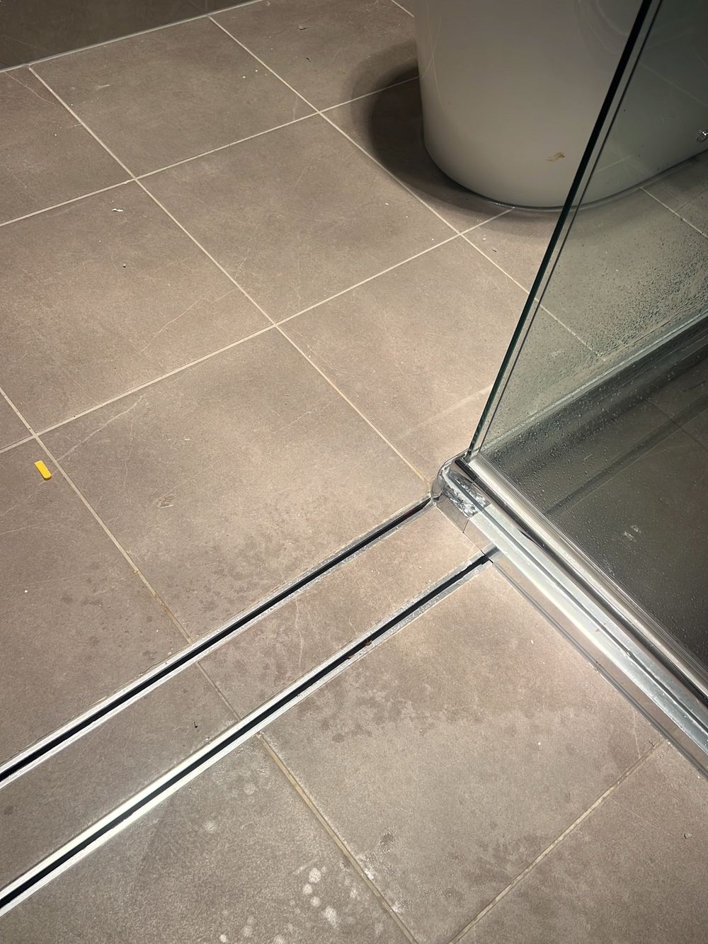 Spoon drain running under the shower hob, found during a handover inspection in Cobbitty